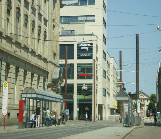 Der Europaplatz in Karlsruhe mit Haltestelle. An einem Tag laufen viele Passanten durch die Karlsruher Innenstadt. Sie kaufen ein, erledigen ein paar Wege und bummeln.