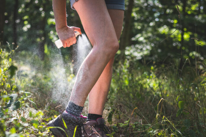 Stechmücken- und Zecken-Spray im Einsatz am Bein eines Wanderers