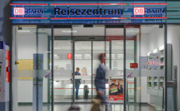 Ein Reisender läuft am Eingang der Deutschen Bahn vorbei