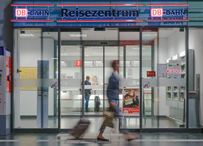 Ein Reisender läuft am Eingang der Deutschen Bahn vorbei