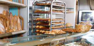 In einer Bäckerei liegen verschiedene Backwaren in der Auslage, auf einem mobilen Wagen und im Hintergrund.