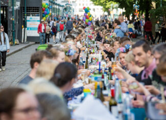 Viele Personen sitzen an einem langen Tisch gemeinsam zusammen und feiern ein Fest