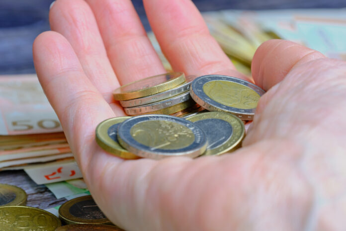 Eine Hand hält verschiedene 1-Euro-Münzen und 2-Euro-Münzen