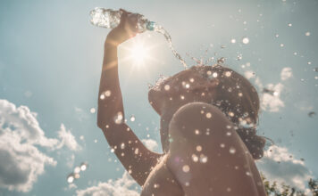 Frau kühlt sich an einem heißen Sommertag mit Wasser ab