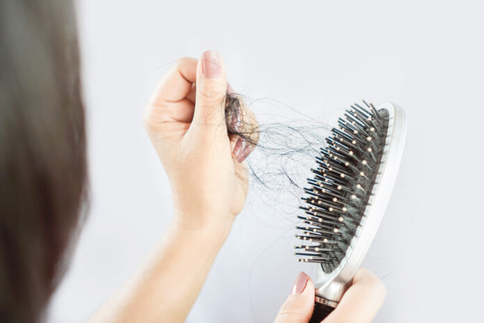 Eine Frau zieht Haare aus der Haarbürste.