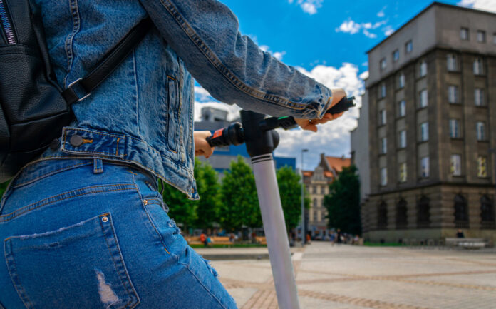 Eine Person fährt auf einem E-Scooter durch die Stadt