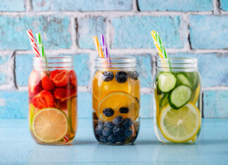 Mehrere Trinkgläser mit verschiedenen Obst- und Gemüsestücken in Wasser mit einem Trinkhalm