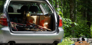 Offene Autotür und Gepäckraum eines Autos voller Angelausrüstung.