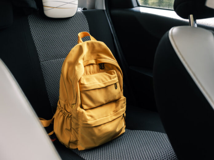Ein gelber Rucksack liegt auf der Rückbank eines Autos.