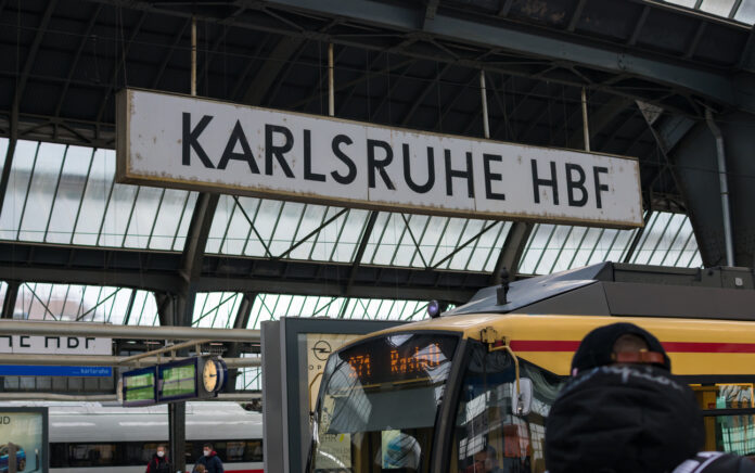 Das Schild vom Karlsruher Hauptbahnhof auf dem Bahnhofsgelände am Bahnsteig