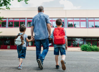 Ein Vater bringt seine Söhne in die Schule.