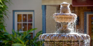 Wasser sprudelt an einem romantischen steinernen Wasserbrunnen herunter