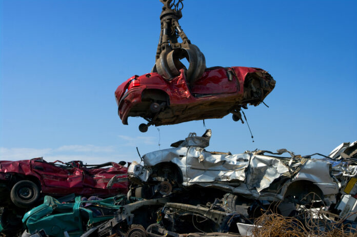 Ein Kran hebt die Karosserie eines Autos.