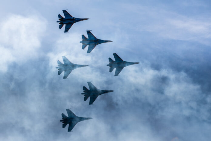 Sechs Kampfflugzeuge fliegen in Formation durch die Wolken