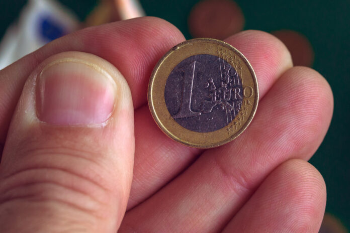 Eine Hand hält eine 1 Euro Münze.