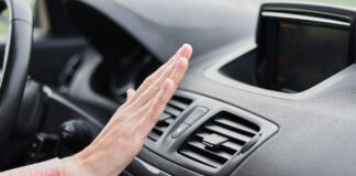 Eine Fahrerin hält ihre Hand vor die Klimaanlage in einem Fahrzeug