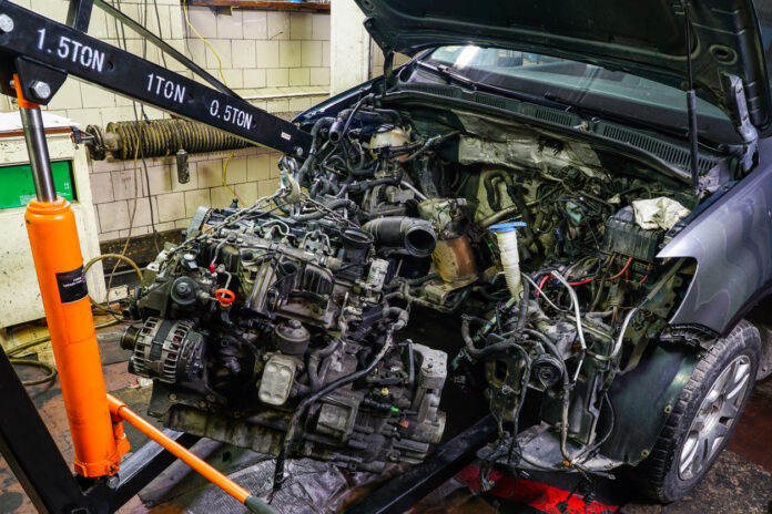 Der Motorraum eines Autos wird mithilfe eines hydraulischen Krans zerlegt.