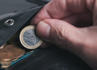 Person zieht 1-Euro-Münze aus dem Kleingeldfach aus einem Geldbeutel.