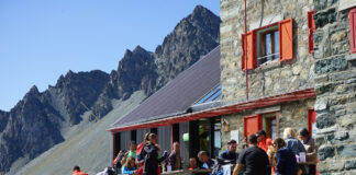 Zahlreiche Urlauber sind auf der Terrasse einer gastronomischen Einrichtung inmitten der Berge