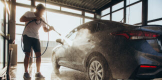 Ein Mann wäscht seinen Wagen mit dem Hochdruckreiniger.