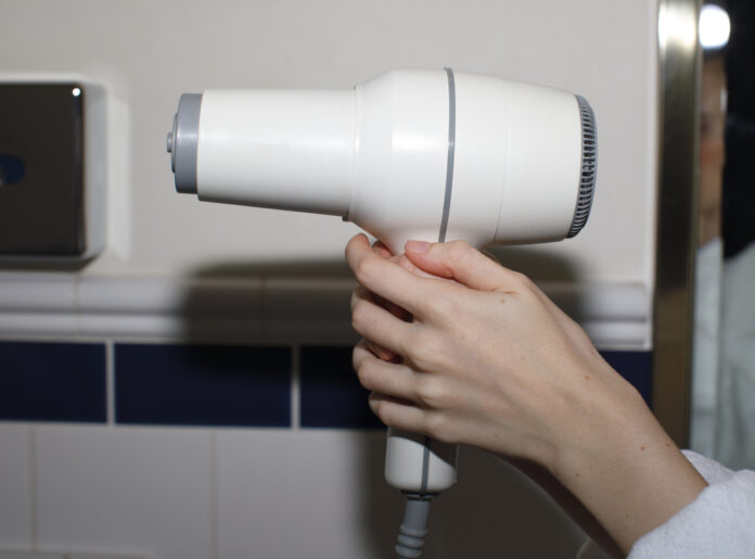 Frau hält einen Föhn in der Hand