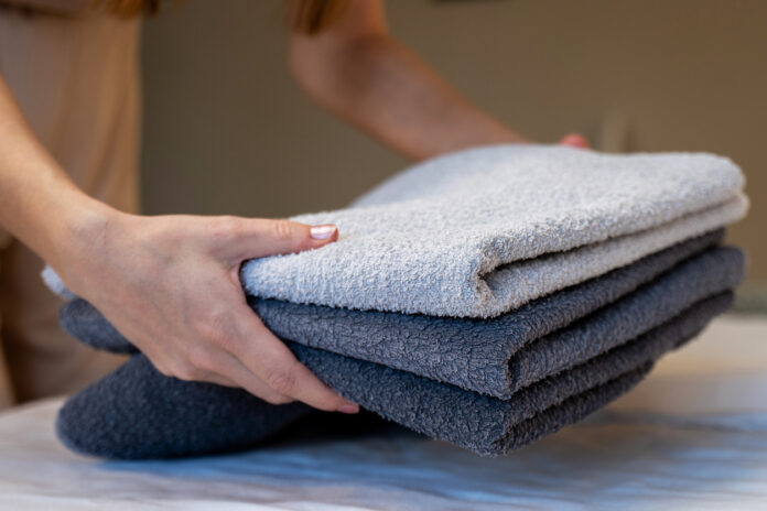 Hände halten Handtücher in einem Hotelzimmer