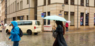 Frau mit Regenschirm läuft durch die Innenstadt von Dresden