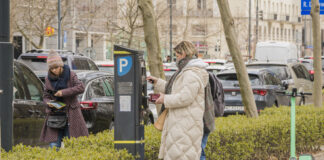 Frau bezahlt Parkticket am Parkautomaten