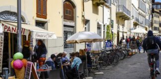 Viele Menschen sitzen im Freien auf den Sitzterrassen der Restaurants und Cafés.