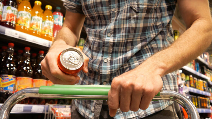 Ein Mann hält eine Getränkedose in der Hand beim Einkaufen.