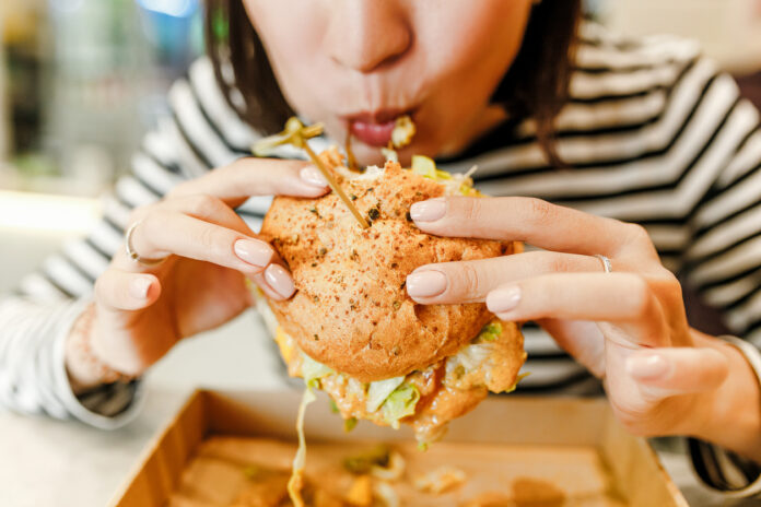 Frau isst einen Burger in einem modernen Fastfood Lokal