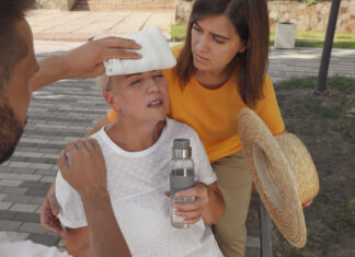 Menschen helfen einer an Hitzeschlag leidenden Frau auf der Straße