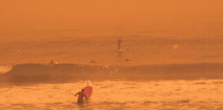 Ein Surfer auf dem Meer während eines roten Sandsturms.