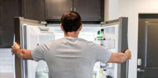 Mann steht vor einem Kühlschrank