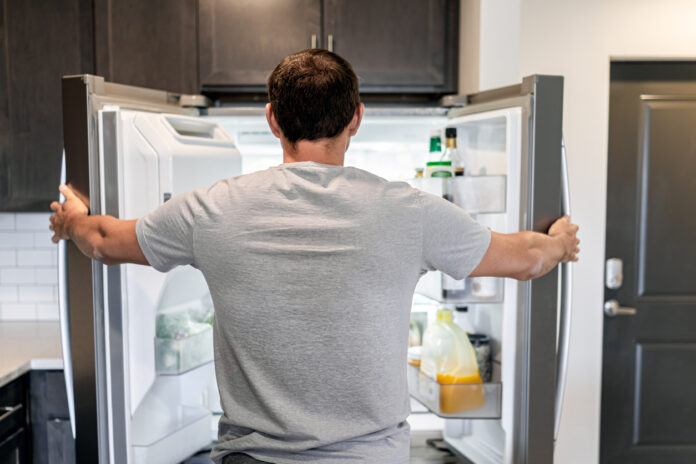 Mann steht vor einem Kühlschrank