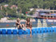 Zwei junge Frauen sitzen auf einer Schwimmmatte auf einem See.