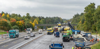 LKW und PKW fahren auf einer Autobahn in beide Richtungen und passieren eine Baustelle. Die Fahrbahn der Bundesstraße oder Autobahn wird erneuert.