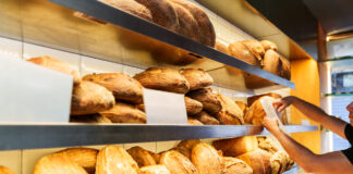 Ein Regal in der Bäckerei mit frischen Backwaren. Auf mehreren Etagen findet man verschiedene Sorten von Brot und einige Paninis.
