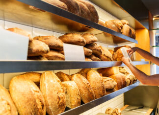 Ein Regal in der Bäckerei mit frischen Backwaren. Auf mehreren Etagen findet man verschiedene Sorten von Brot und einige Paninis.