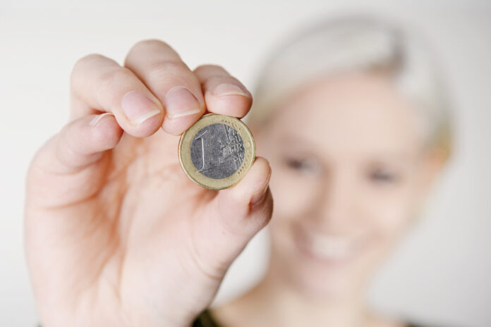 Eine Frau hält eine 1-Euro-Münze.