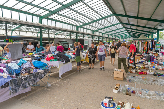 Einige Besucher eines Flohmarkts schlendern an den Ständen vorbei. Flohmarkthändler bieten ihre Waren an: Gebrauchtwaren, Sammlerstücke, Kostbarkeiten, Skurriles und Gebrauchtes. Die Gäste und Sammler kommen von nah und fern.