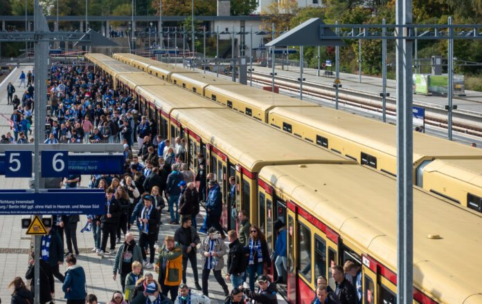 Viele Passagiere drängen sich auf einem Bahnsteig. Man versucht umzusteigen, aber es ist eng. Im Bahnhof halten zwei Berliner S-Bahnen aus dem die Leute strömen.