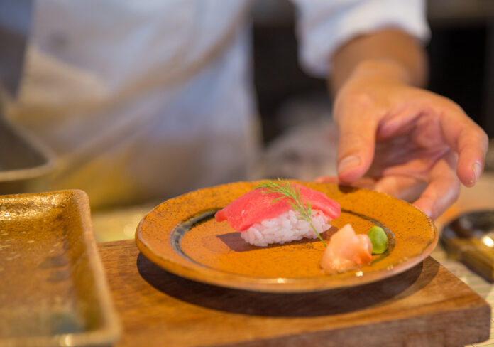 Ein Koch serviert Sushi.