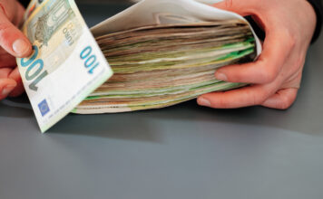 Ein Mann hält einen Geldumschlag mit vielen Geldscheinen darin.