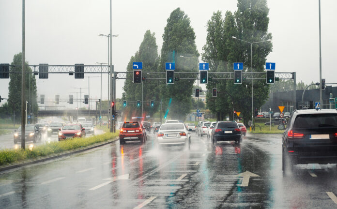 Autos fahren im Regen an einer Ampel vorbei.
