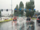 Autos fahren im Regen an einer Ampel vorbei.