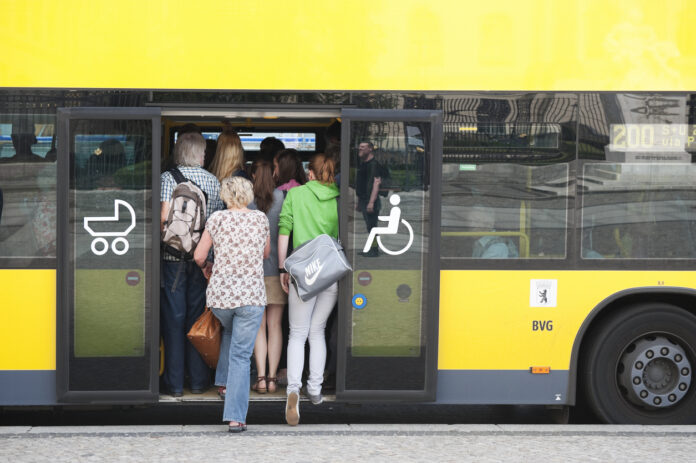 Viele Menschen quetschen sich in einen gelben Bus.