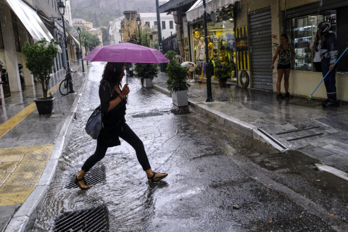 Frau mit Regenschirm überquert Straße im Regen