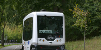 Ein selbstfahrender Bus fährt allein auf der Straße im Straßenverkehr. Das Fahrzeug fährt selbstständig, ohne Fahrer. Es funktioniert wie ein intelligenter Roboter.