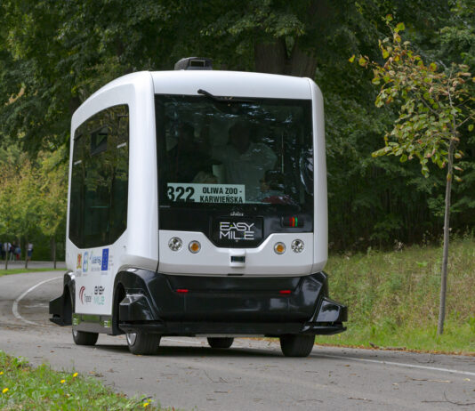 Ein selbstfahrender Bus fährt allein auf der Straße im Straßenverkehr. Das Fahrzeug fährt selbstständig, ohne Fahrer. Es funktioniert wie ein intelligenter Roboter.